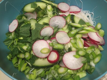 add sliced vegetables and herbs to noodles